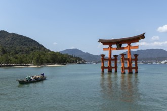 An excursion boat with tourists passes through the torii in the water, sight, tourist attraction,