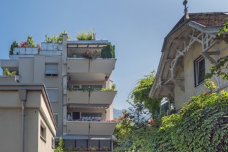 Grey façade, green flat roof and concrete balconies with floral decorations and old villa,