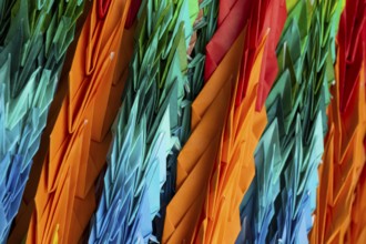 Chains of colourful origami cranes made of paper as a sign of peace in the Peace Park, close-up,