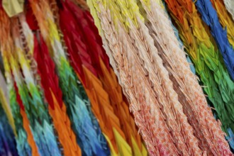 Chains of colourful origami cranes made of paper as a sign of peace in the Peace Park, close-up,