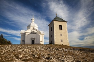 White church and tower in an open landscape under a blue sky with clouds, Mikulov Nikolsburg Czech