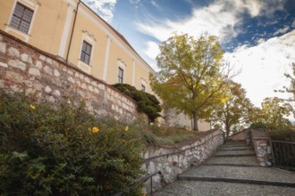 An idyllic path with stone steps and autumn trees leads to a yellow building, Mikulov Nikolsburg