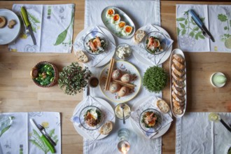 A stylishly laid table with a selection of fresh dishes, decorated with herbs and candlelight,