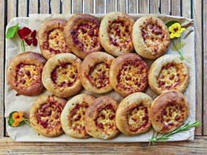 Small pizzas on baking board decorated with flowers and rosemary, bird's eye view, Lower Austria