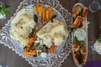 A cheese platter with different types of cheese and dumplings, decorated with herbs on a wooden