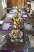 A long table with a table setting in a rustic room, decorated with flowers and crockery, Lower