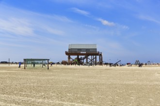 Pile dwelling, toilet block on the beach, football goal, walkers on the horizon, Sankt