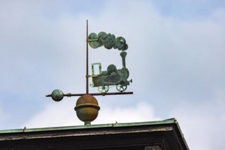 Steam locomotive with lots of smoke. Weather vane on the roof of the main railway station.