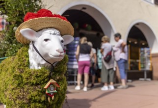 Kitsch in Black Forest style. A sheep with a Bollenhut and cuckoo clock. Freudenstadt,