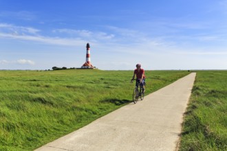 Cyclist, cycle tour through salt marshes, Westerheversand lighthouse on the horizon, Cirrus,