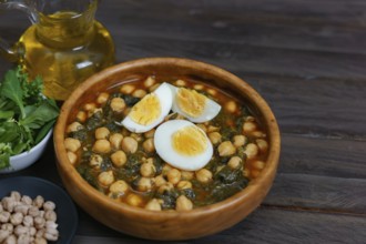 Wooden bowl with chickpeas with spinach and hard-boiled egg on wooden table