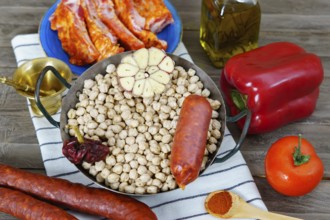 Raw chickpeas in a casserole with the ingredients to make the stew