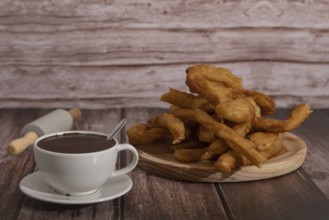 Cup of hot chocolate with freshly made churros on wooden background typical spanish breakfast on