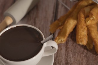 Cup of hot chocolate with freshly made churros on wooden background typical spanish breakfast on