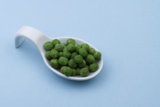 White ceramic spoon with peas and blue bottom
