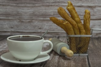 Cup of hot chocolate with freshly made churros on wooden background typical spanish breakfast on