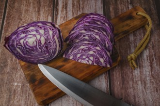 Close-up of a red cabbage or purple cabbage cut with a knife on a wooden board