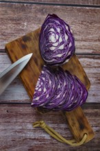 Close-up of a red cabbage or purple cabbage cut with a knife on a wooden board