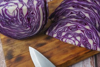 Close-up of a red cabbage or purple cabbage cut with a knife on a wooden board