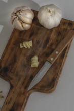 Whole and peeled garlic on wooden board and white background