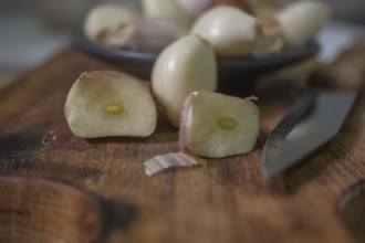 Whole and peeled garlic on wooden board and white background