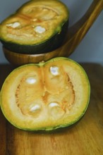 Green pumpkins cut in half on wood and white background