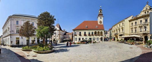 Panoramic view of a town square with historic clock tower and surrounding buildings under a clear