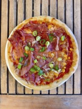 Pizza with ham, spring onions and cheese served on a wooden base. Italian flavours with fresh