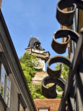 Architecturally richly decorated tower behind a forged fence with a clear sky Graz Clock Tower Graz