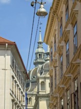 Historic buildings and a church tower under a blue sky, bustling urban atmosphere Landhaus Graz