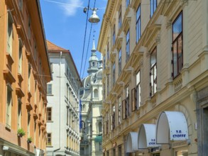 Lively old town alleyway with historic buildings and church tower in the background Landhaus Graz