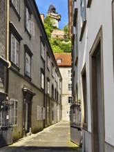 Narrow alleyway in the historic city centre, lined with old buildings with a tower in the