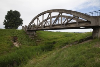 A concrete bridge over a grassy landscape that radiates peace and serenity Perschling flood channel