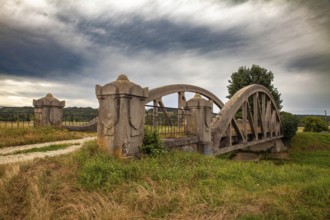 A stone bridge with dramatic clouds in the background, embedded in a rural landscape Perschling