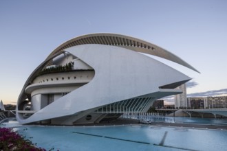 Building with curved white design next to a turquoise-coloured pool under the evening sky Opera