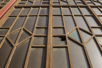 A window with broken glass and a complex metal structure
