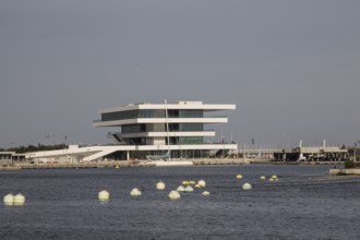 Modern building with clean lines on the water, surrounded by buoys