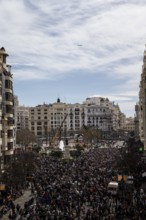 Large crowd in a city in front of tall buildings and a slightly cloudy sky MascletÃ¡ de Fallas