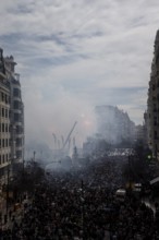 Dense crowds in the city with rising smoke and buildings MascletÃ¡ de Fallas