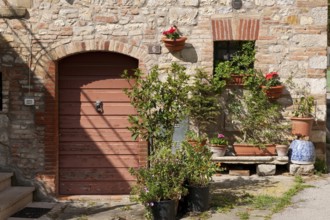 Tuscany country house detail with flower bench planter next to old wooden door quarry stone wall,