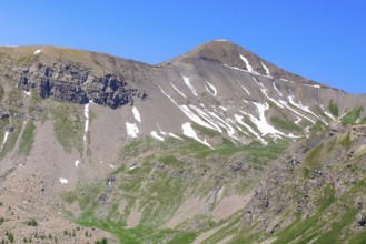 View to the rear eroded steep rocky slope mountainside slope with gravel rock thawing snow remains