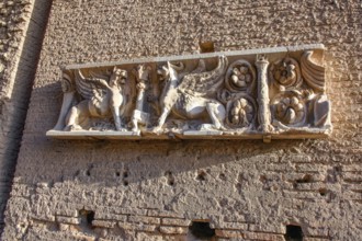 Half relief with mythical figures winged creatures griffins on brick wall of ancient building on