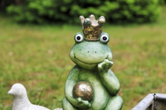 Sculpture of a frog king with crown and golden ball, decoration in the garden, Schloss