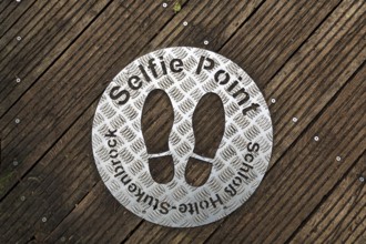 Selfie point, metal plate, shoe prints on a plank path at the source of the River Ems near Schloss