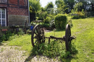 Rusted metal wheels on an axle, decoration in a garden, country inn in summer, Rischenau, LÃ¼gde,