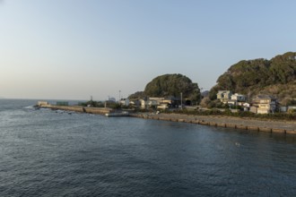 Residential houses on the coast in the evening light and mountain landscape in the harbour of