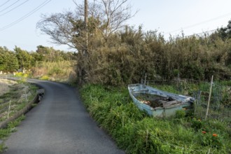 Old wooden boat on the side of a road in a rural landscape in the evening light, Hota, Kyonan,