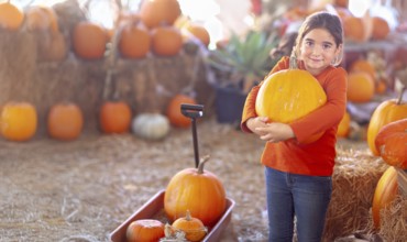 Young girl choosing A pumpkin at A pumpkin patch on a fall day