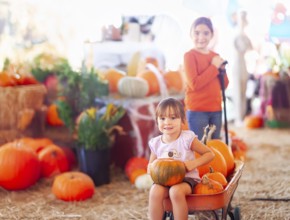 Two sisters enjoying a wagon ride at a pumpkin patch on a fall day