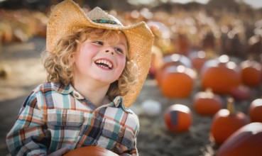 Cute young boy wearing cowboy hat at pumpkin patch farm